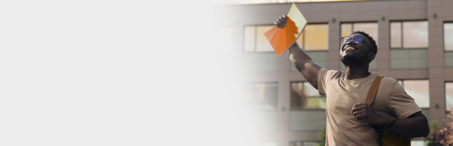 male student celebrating outside of university