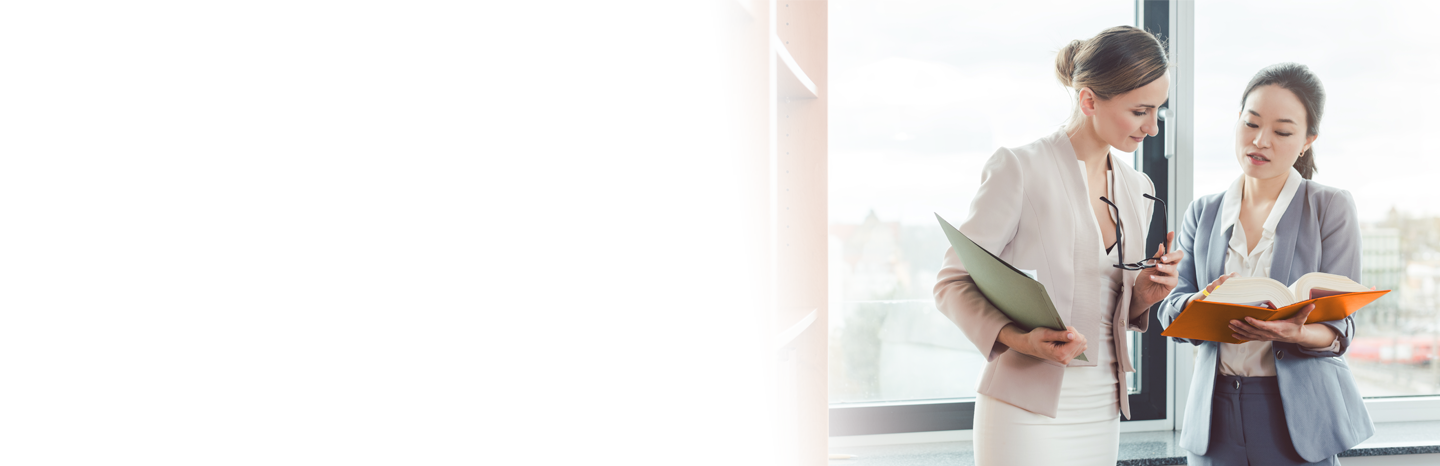 Two female lawyers looking at a book in an office