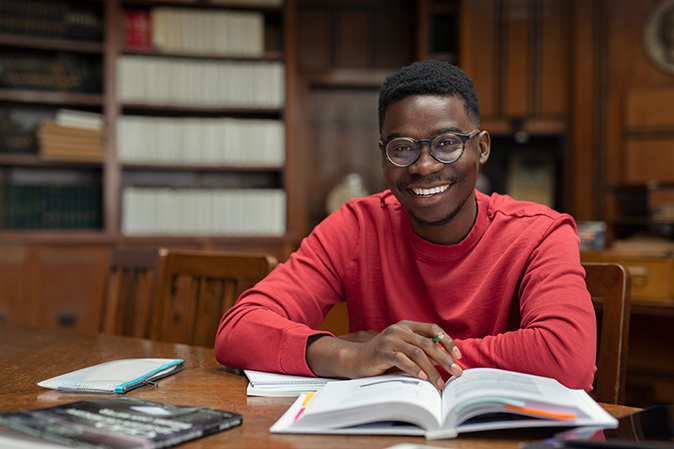 Young man smiling while studying in the college library